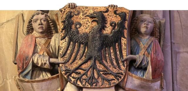 Auf goldenem Schild: der Adler gehalten, oder besser getragen, ja überflügelt von zwei bunt gefassten Engeln. Die Himmelsboten stehen in Heilbronn dem Wappentier nicht selten bei.