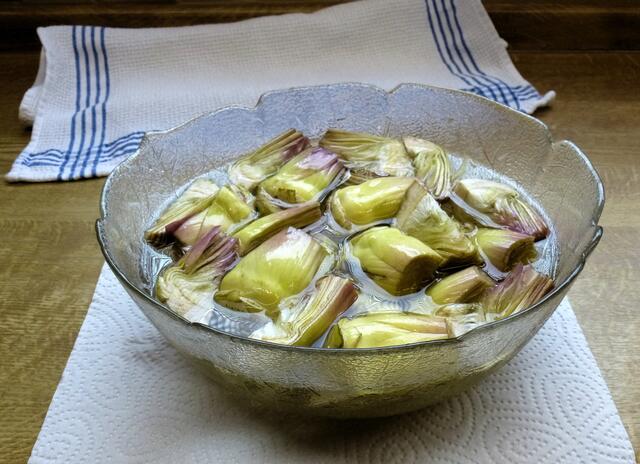 Das Wasser abgießen und die Artischockenviertel mit reichlich Küchenpapier trocknen. In einer großen Pfanne 800 ml Sonnenblumenöl erhitzen.