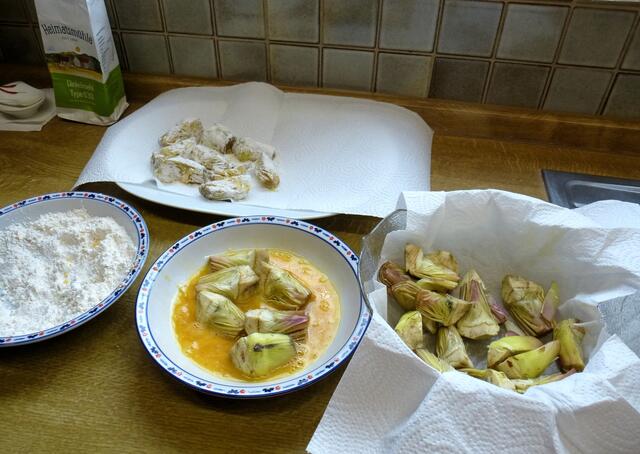 Je einen tiefen Teller mit Mehl bzw. mit 2 verrührten Eiern (+ 1/4 Teelöffel Salz)   füllen. Eine Platte dick mit Küchenpapier belegen. Die Artischocken erst in die Eimasse ,  dann ins Mehl tauchen. Auf der Platte ablegen.