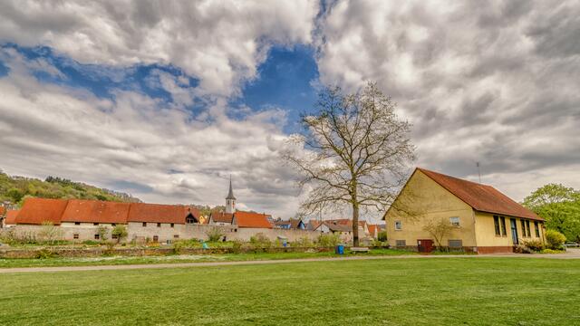Blick auf die Sindringer Stadtmauer und die Heilig-Kreuz-Kirche, im Vordergrund ist die alte Turnhalle zu sehen.