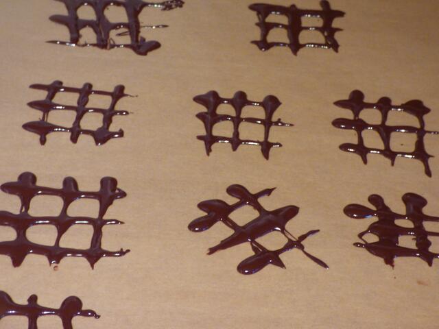 Schokogitter herstellen: dazu die geschmolzene Schokolade mit einem kleinen Löffel auf ein Backpapier träufeln, etwas ziehen. | Foto: sigischlottke