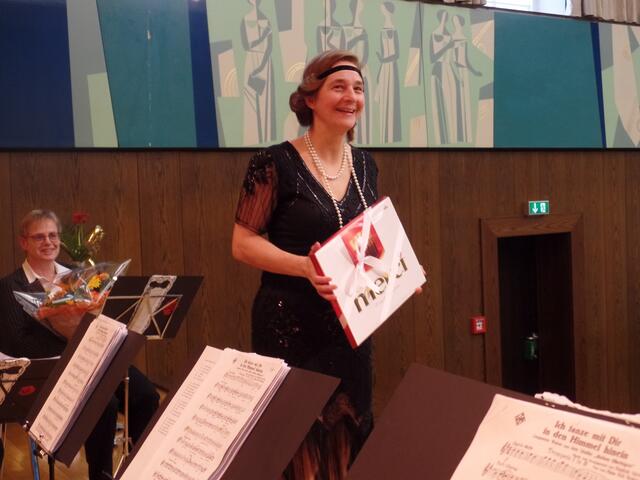 Yvonne Diebel überreicht ein Präsent im Namen des Orchesters an den Dirigenten Andreas Benz.