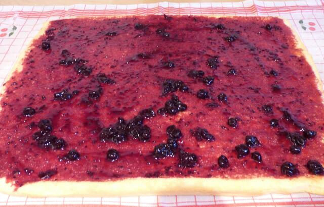 Nun die Küchenrolle entfernen und die vorbereitete Marmelade erst mit dem Löffel verteilen und dann mit einem Pinsel gleichmäßig verstreichen.