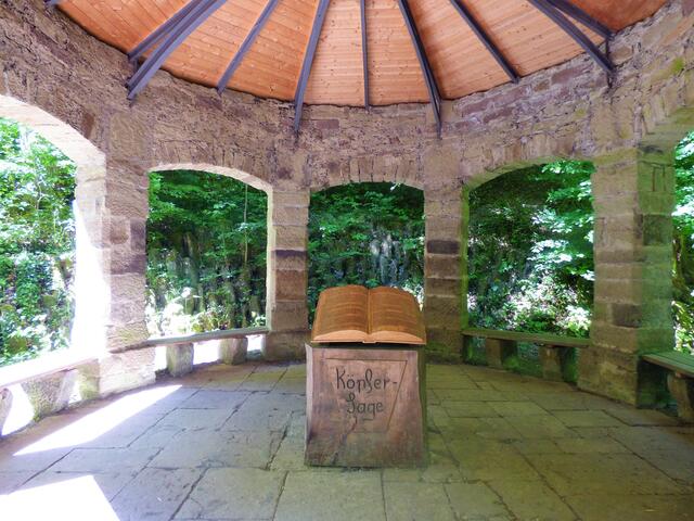 Ein Blick in das Innere des Musikpavillons mit dem hölzernen Pult und dem Buch mit der Köpfersage.