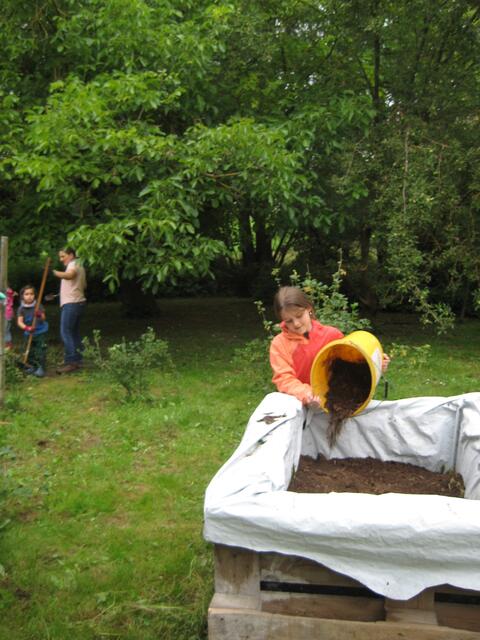 Emily befüllt das Hochbeet mit Kompost.