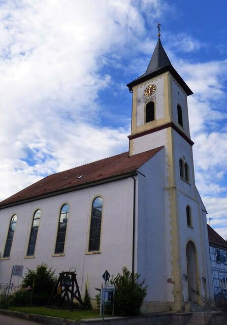 Die kath. Kirche St. Georg und daneben die alte Glocke von 1810