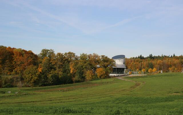 Bunte Wälder und der Gemü Dome. Die Turmspitze folgt dem Lauf der Sonne, wodurch die Sonne optimal auf die Solarmodule strahlen kann.