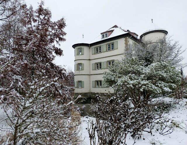 Zwischen den verschneiten Sträuchern und Bäumen wirkt das Wasserschloss richtig romantisch.
