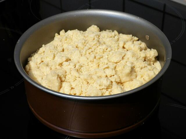 Den restlichen Streuselteig mit den Fingern über den Äpfeln verteilen.