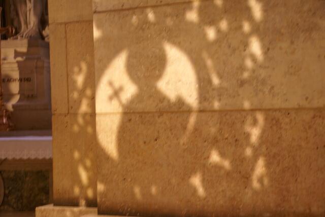 Licht vom Kirchenfenster malt den Schatten an die Wand