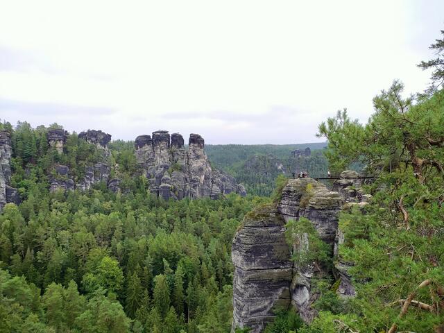 In luftiger Höhe führt ein schmales Brückchen zu einem Aussichtsfelsen.