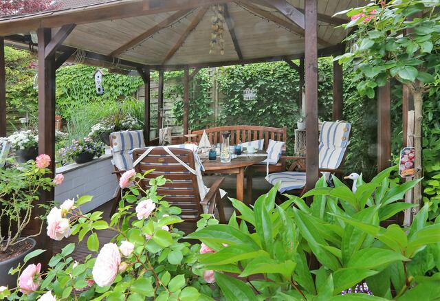 Ein geschützter Sitzplatz unterm Laubendach gibt sich ebenso charmant wie die stimmig angeordneten Details. | Foto: Guido Sawatzki