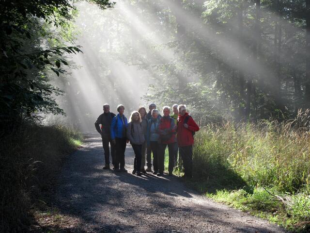 Die Wandergruppe in den Nebel-Sonnen-Strahlen mit strahlenden Gesichtern am frühen Morgen