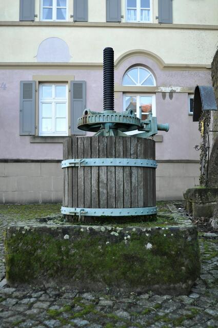 Alte Traubenpresse. Rechts sieht das Eisenkreuz. Dahinter das alte Backhaus. Da sieht man auch die verschiedenen Fensterformen. | Foto: Daniela Somers
