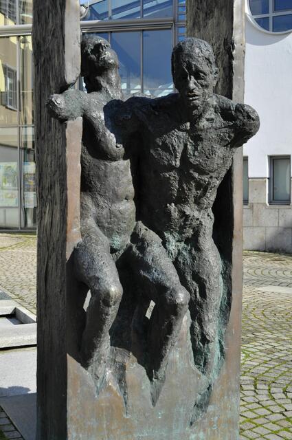 Skulptur vor dem Rathaus:  Bronzeskulptur "Im Zeitkanal" der Ludwigsburger Künstlerin Michaela A. Fischer, verankert über einem Miniaturwasserkanal, ihren festen Platz gefunden. So wie das Wasser in einer begradigten, künstlichen Enge fließt, empfindet die Künstlerin die Situation ihrer Figuren; sie zwängen sich zwischen zwei Wänden hindurch, als einem Symbol für die zunehmend größer werdenden Anforderungen und Erwartungshaltungen. Quelle: www.kirchheim-neckar.de/die-gemeinde-kirchheim/rundgang/rathaus/ | Foto: Daniela Somers