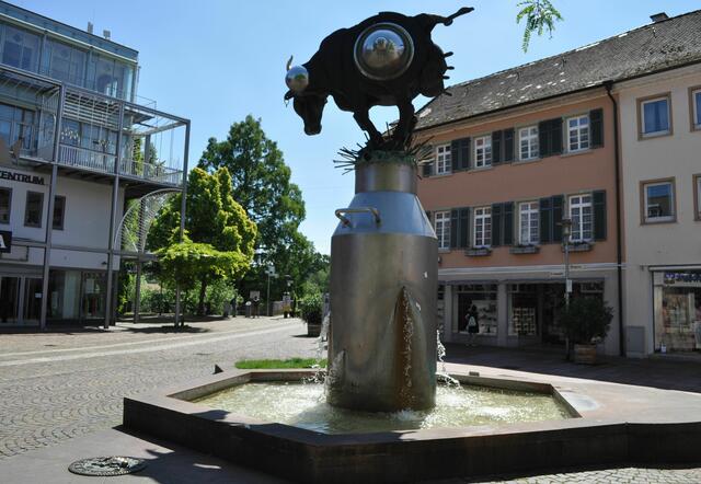 Am Kronenplatz begegnet man dann wieder der Kunst von Jürgen Goertz. Diese Kunstwerk heißt das Kuhriosum. Der Brunnen mit Milchkanne als Sockel und dieser Kuh, Halb Tier halb Maschine, ist ein Hingucker. | Foto: Daniela Somers