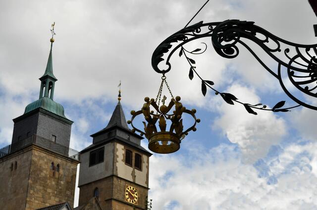 Schild des Gasthaus Krone. Im Hintergrund die Kirchtürme der Bartholomäuskirche. | Foto: Daniela Somers