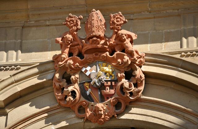 Das Wappen über dem Eingang. In der Mitte das persönliche Wappen von Knittel. Ein redendes Wappen. Es sagt also etwas aus. Denn ein Knittel kann auch ein Knüppel sein. Und so sieht man einen Arm der einen Knüppel schwingt. | Foto: Daniela Somers
