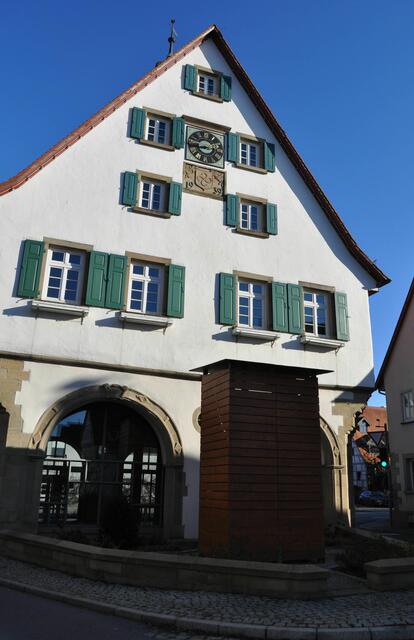 Dieser Holzkasten ist schon ein wenig kurios. Denn eigentlich steht das "Taubedenkmal" dort. Ein Geschenk des Hofbildhauers Ludwig von Hofer an die Gemeinde. Es stellt  zwei Brüder, die Grafen von Taube, dar, die im Krieg 1870/71 in Frankreich gemeinsam den Tod fanden und wurde in  Carrara-Marmor ausgeführt. Warum es nun hinter Holzverkleidung verschwunden ist, bleibt zu spekulieren. Dahinter ist es aber noch zu sehen. | Foto: Daniela Somers