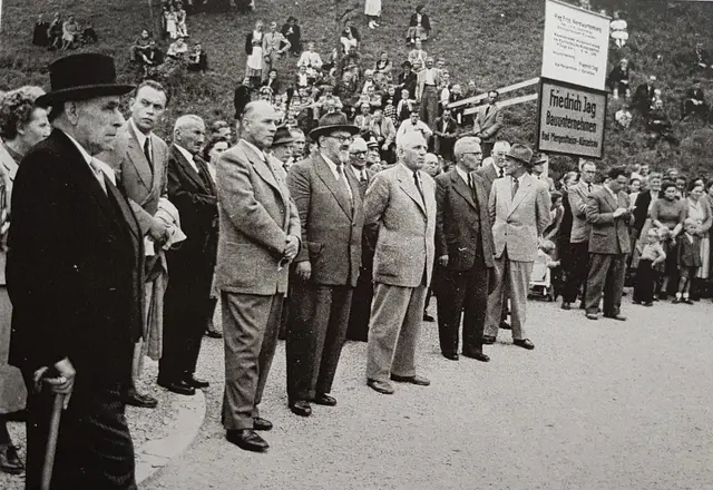 Viel Prominenz war zur Brückenweihe angereist, sogar Innenminister Fritz Ulrich (1888 - 1969 ) kam aus Stuttgart nach Kocherstetten (der Herr im dunkelgrauen Anzug, mit Hornbrille und Hut). 
Wer wohl der Herr mit Block und Stift war? 
Im Hintergrund der mit Schaulustigen bevölkerte Hang, der 1955 noch nicht bewaldet war. | Foto: Sammlung Lore Kirchdörfer