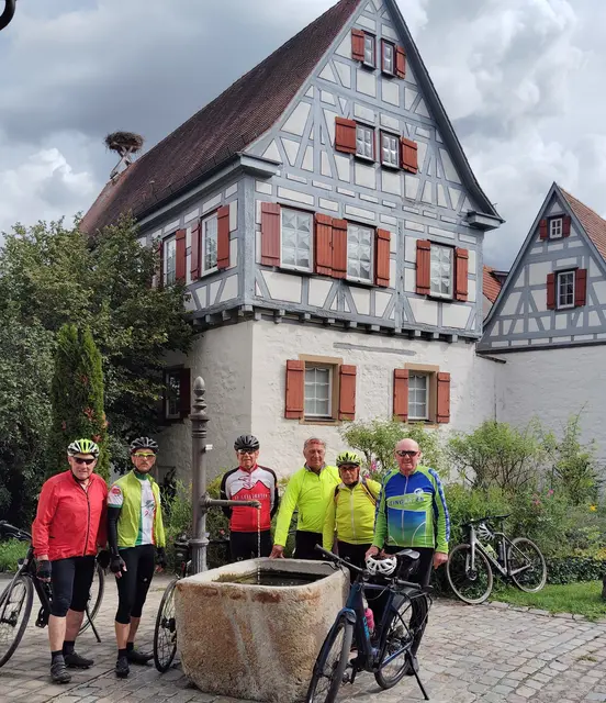 Radsportler vom SV Leingarten vor einer kleinen Fachwerkidille mit Dorfbrunnen in Freiberg am Neckar | Foto: Urheberbild von Willi Frasch