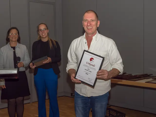 Matthias Schäfer zeigt die Urkunde des Goju-Ryu Karatebundes Deutschland, die er zur Verbandsehrennadel in Platin erhielt (im Hintergrund -v.l.- Judith Niemann, Öffentlichkeitsarbeit, und Geschäftsführerin Rebecca Niggl) | Foto: Karateverein Eppingen