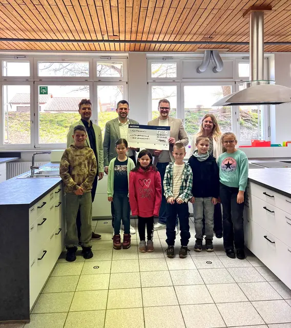 v.l.n.r: Hauptamtsleiter Florian Bausch, Matthias Hruby von der Baden-Württembergischen Bank Heilbronn, Bürgermeister Kai Kraning und Schulleiterin Katja Heim. In der zweiten Reihe freuen sich die Kinder der Lichtenbergschule, die sich besonders über die neue Küche freuen. | Foto: Gemeinde Oberstenfeld