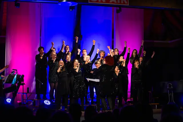 Chor auf der Bühne singt halten die geballte Faust nach oben als Teil der Choreoeografie
