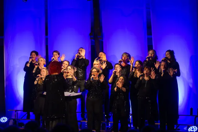Chor auf der Bühne singt mit Choreografie