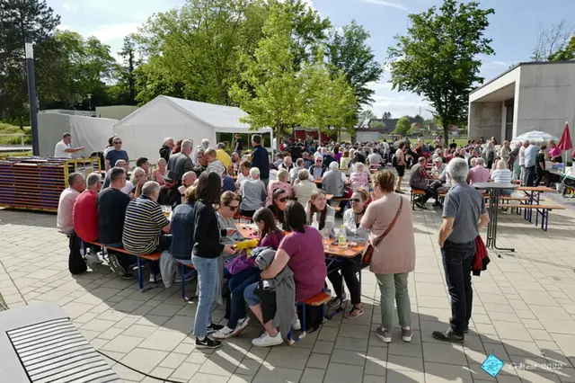 Viele Menschen sitzen auf Bierbänken zusammen