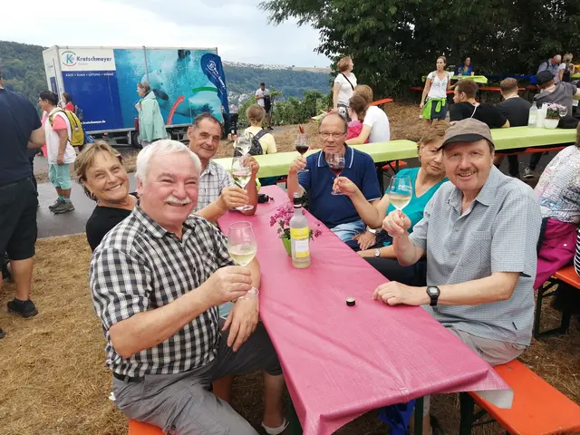 Menschen sitzen im Freien und stoßen mit Weingläsern an
