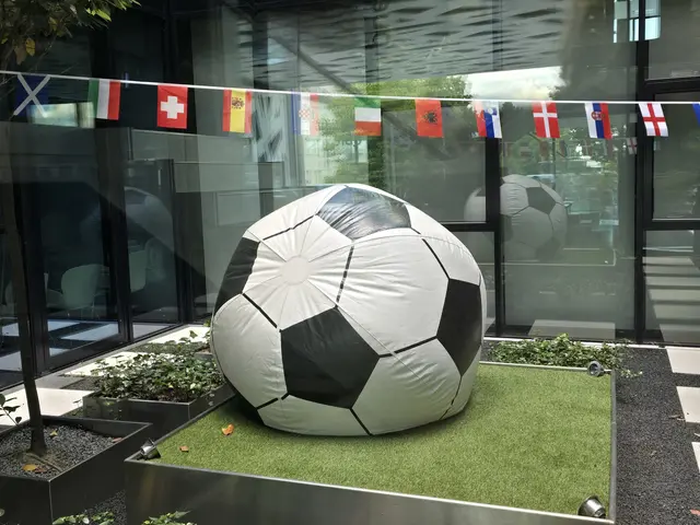 Aufgeblasener Fußball mit Länderfahnen auf einer Leine darüber