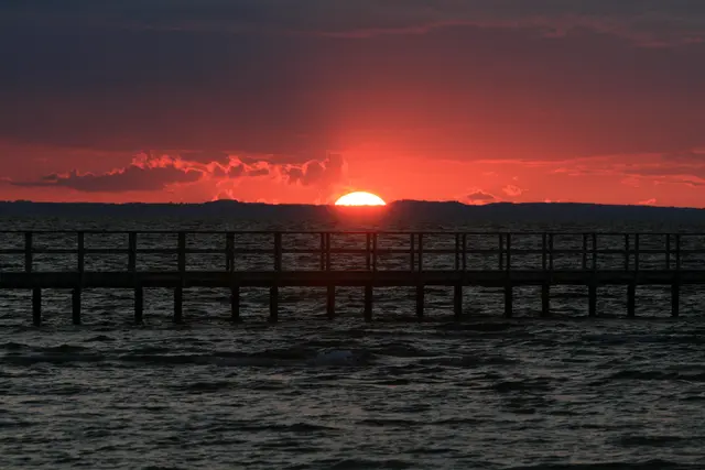 Sonnenuntergang vor einer Seebrück in Schweden mit magischem roten Himmel