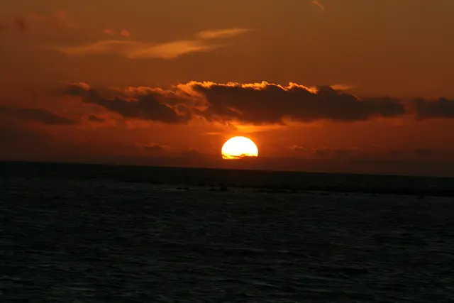 Sonnenuntergang am Öresund / Schweden. Die Sonne versinkt im Meer bei bewölktem Himmel.
