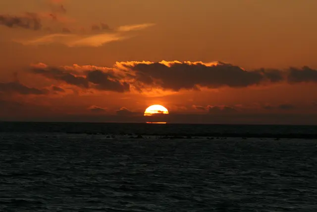 Sonnenuntergang am Öresund / Schweden. Die Sonne versinkt im Meer mit bewölktem Himmel.