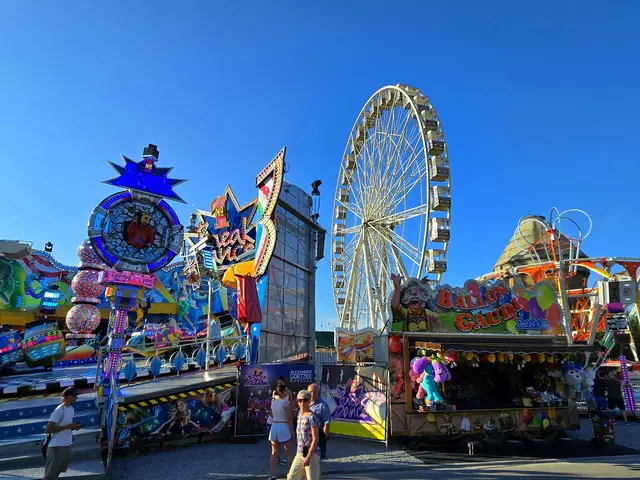 Riesenrad und bunte Fahrgeschäfte mit einigen Besuchern 